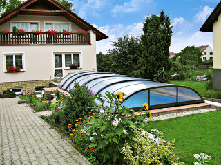 Zastřešení bazénu ELEGANT NEO™ díky své menší výšce nenaruší celkový vzhled Vaší zahrady Zastřešení bazénu ELEGANT NEO™ v zahradě rodinného domu